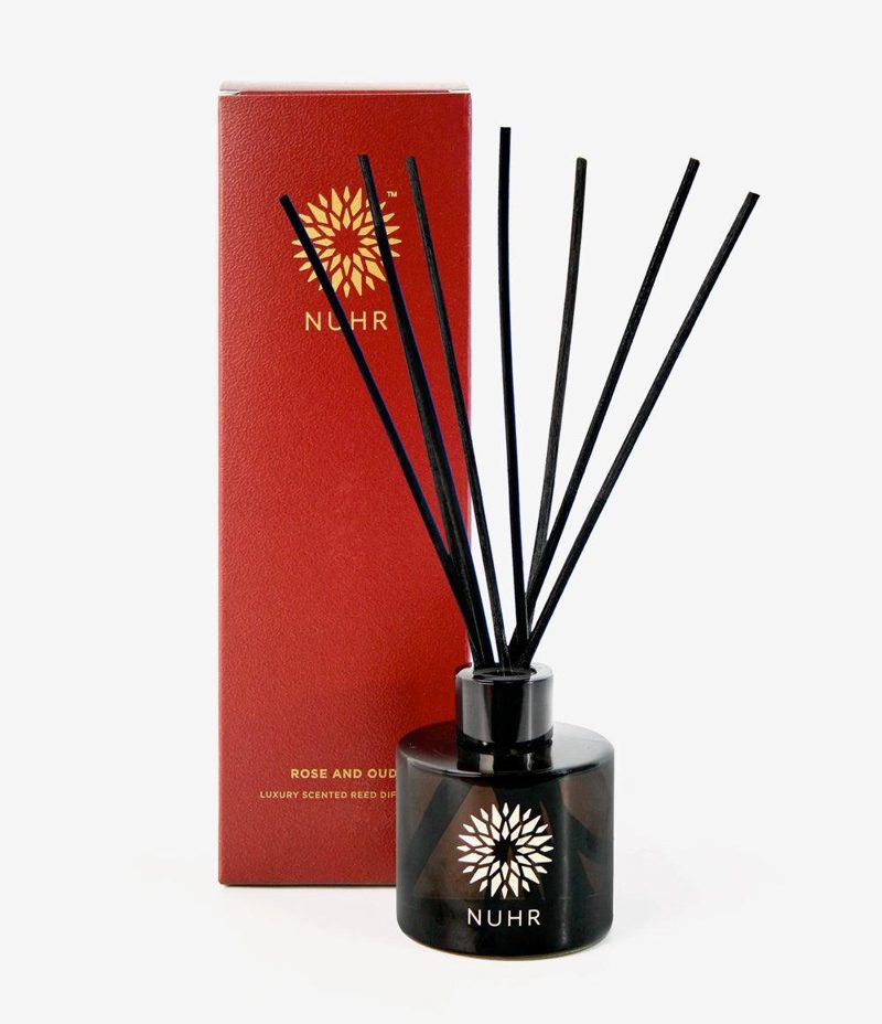 NUHR Home Rose and Oud luxury reed diffuser with black reeds beside its red gift box