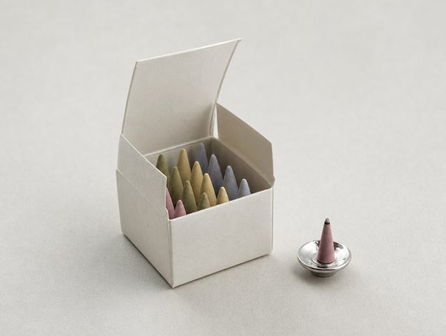 Illustrative small paper box of pastel Japanese incense cones beside a silver holder